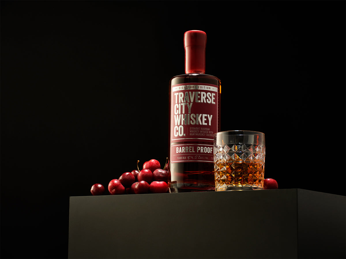 Barrel Proof Cherry bottle with a glass of whiskey and fresh cherries