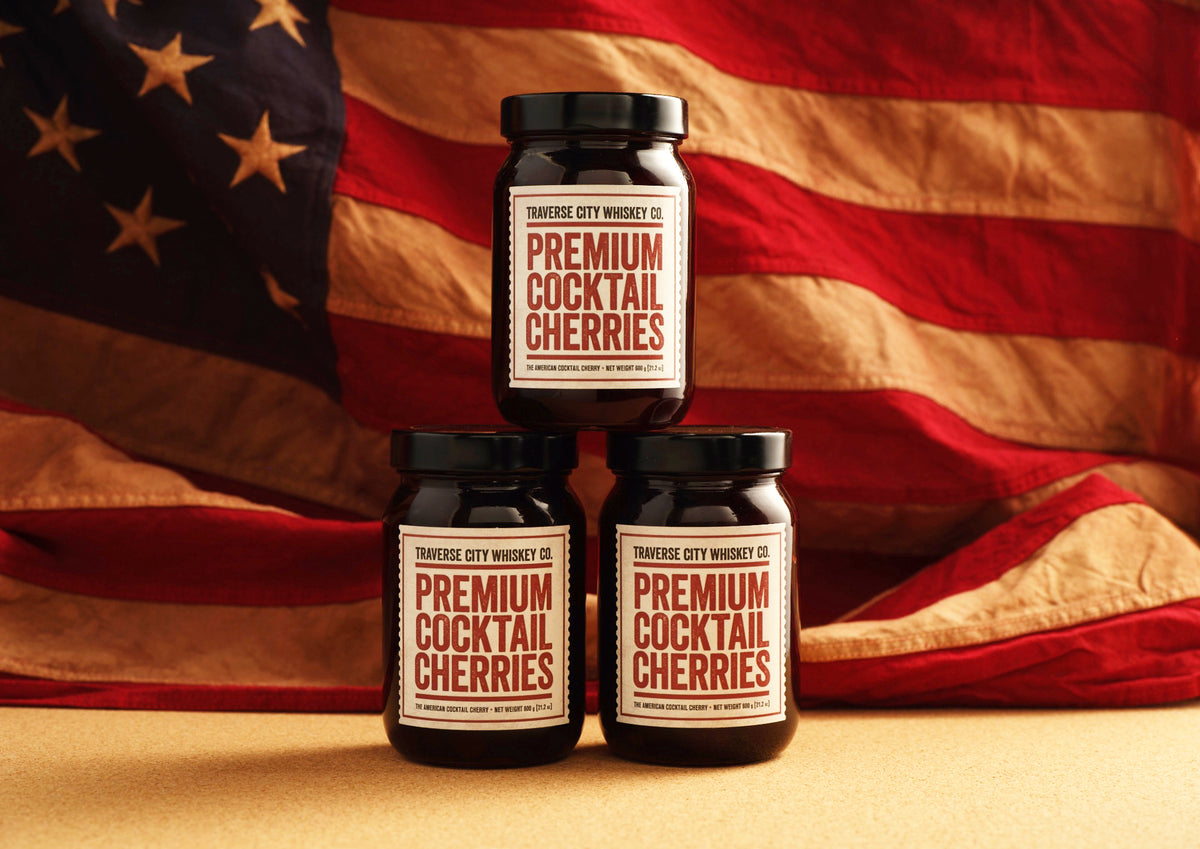 Three jars of Premium Cocktail Cherries in front of an American flag