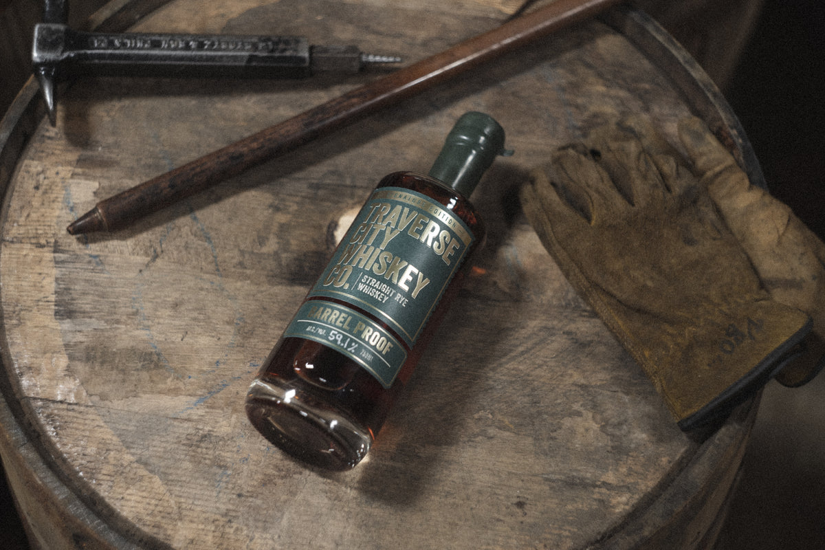 Barrel Proof Rye bottle on a barrel head with work gloves