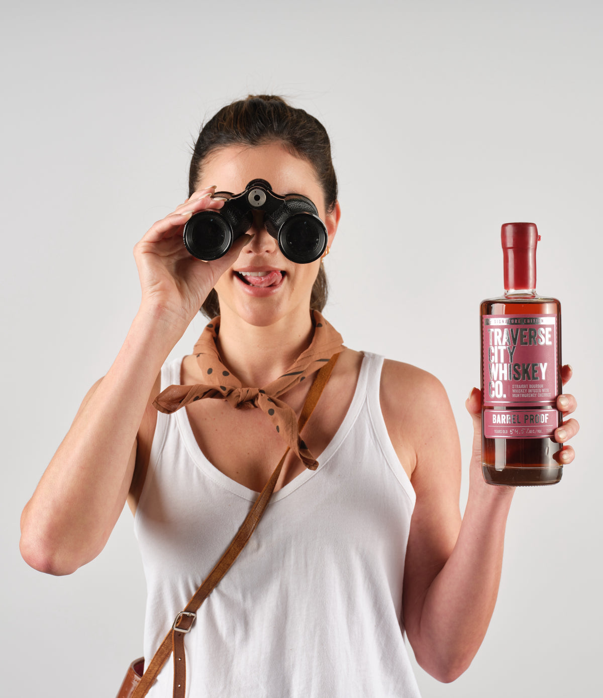 Woman with binoculars holding a bottle of Barrel Proof Cherry