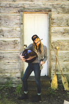 Woman carrying a basket of cherries outside a log cabin