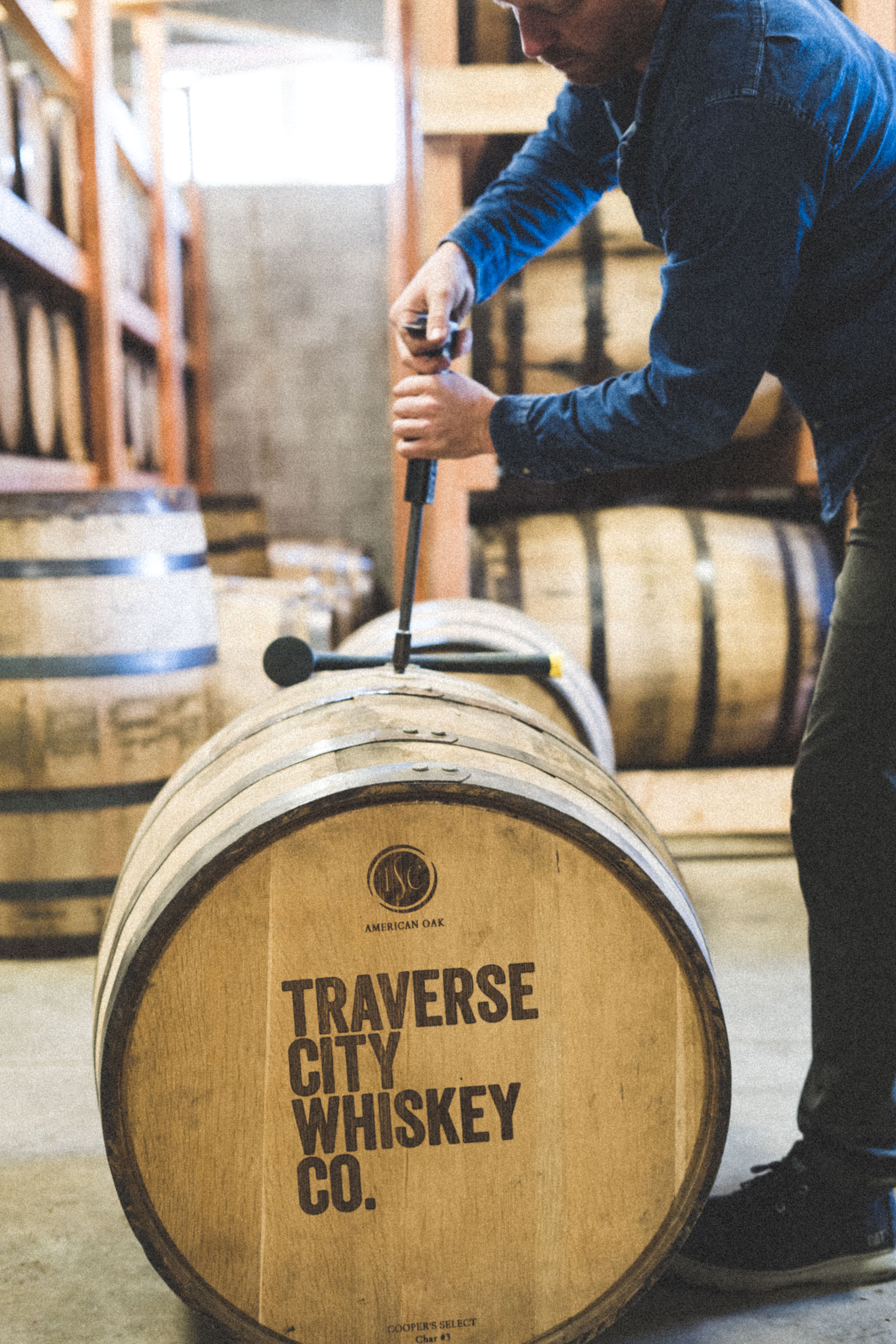 Distiller working with a whiskey barrel in the rickhouse