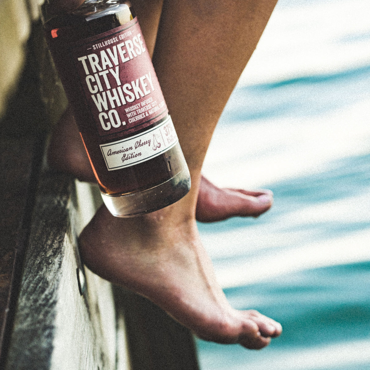 American Cherry Edition bottle on a dock above the water
