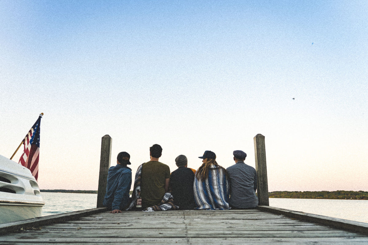 Friends sitting on a dock at sunset