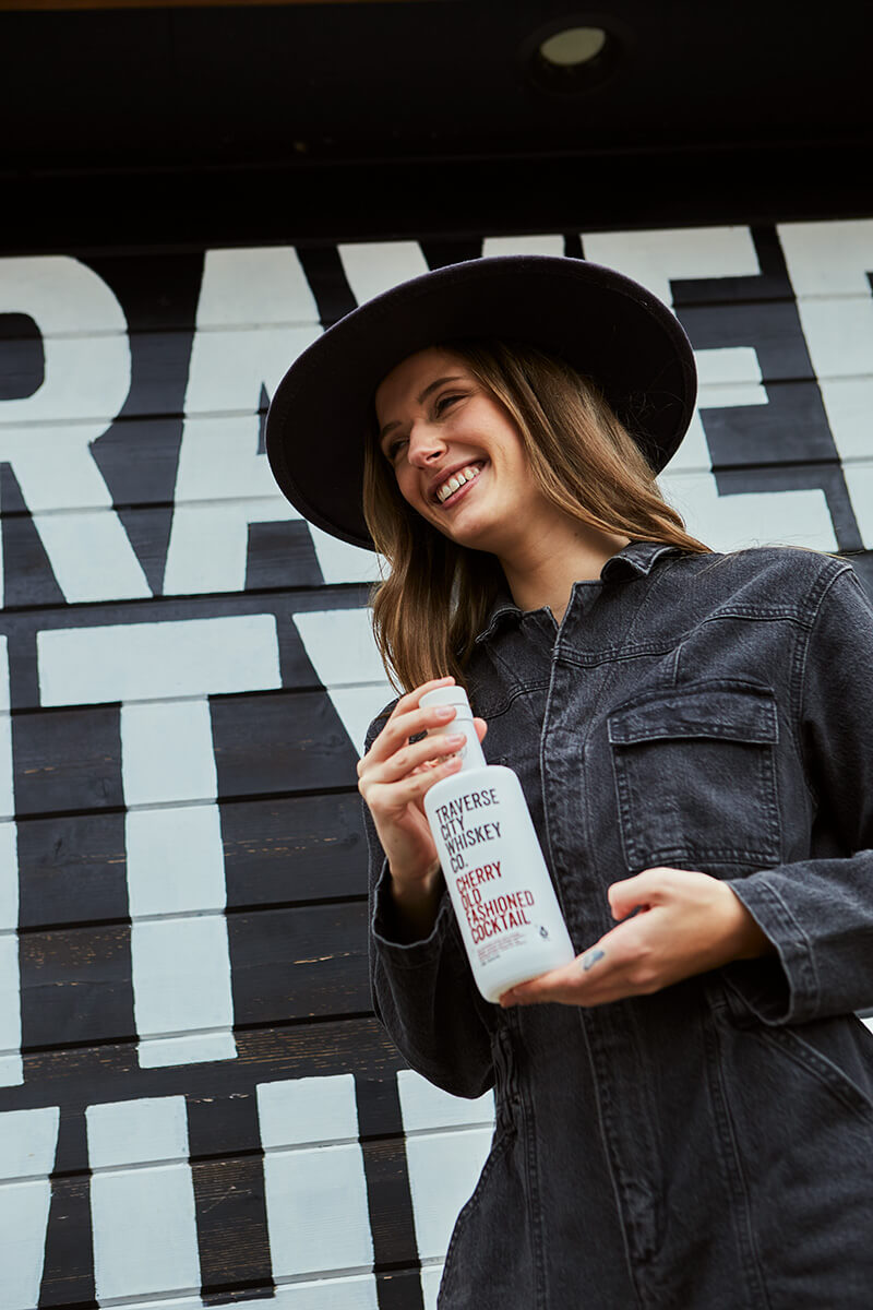 Woman holding a bottle of Ready-to-Serve Cherry Old Fashioned