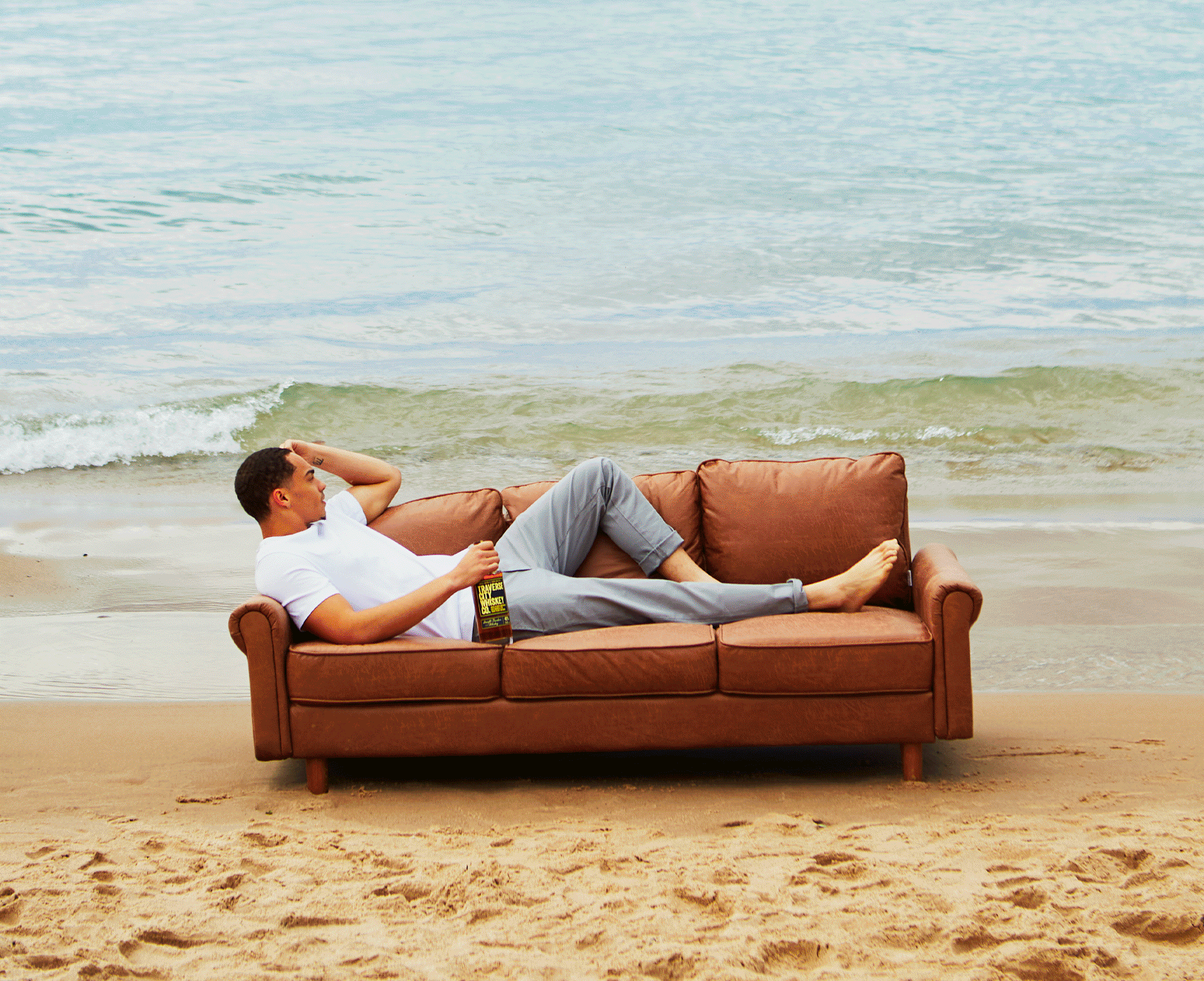 Rotating photos of friends with whiskey on a leather couch around northern Michigan: a beach, pine woods, an autumn field, a red barn and the rickhouse