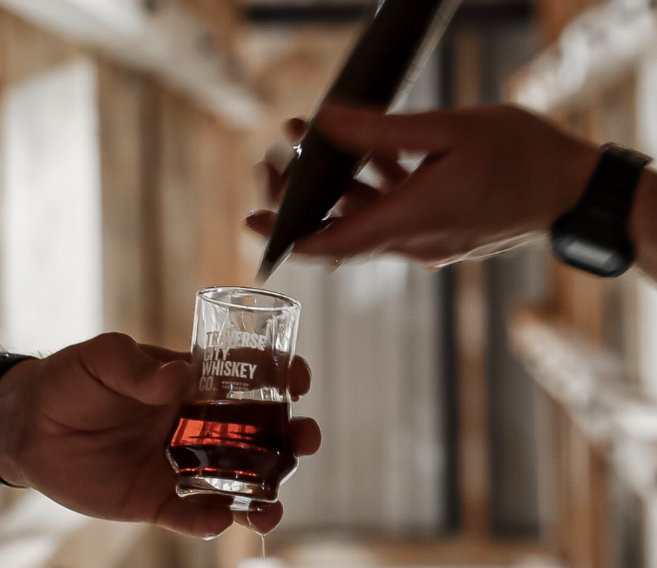 Whiskey drawn from a barrel with a barrel thief into a tasting glass