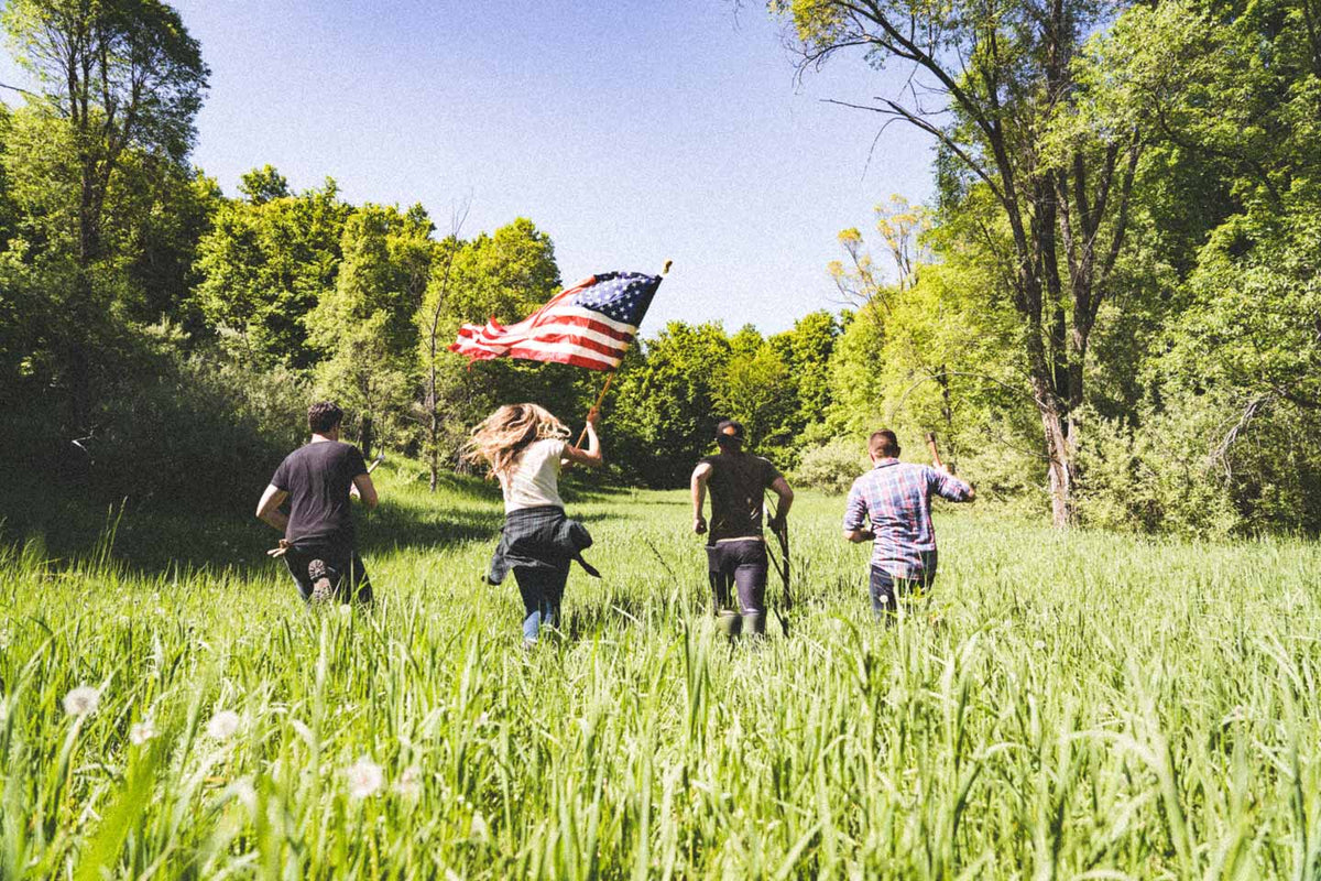 Friends running through a meadow with an American flag