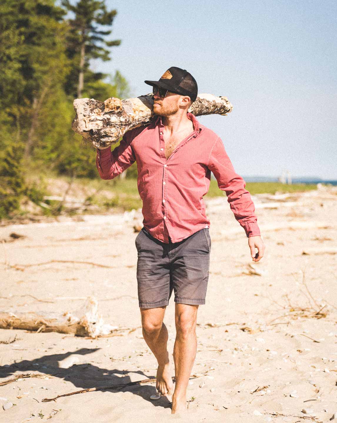 Man carrying driftwood along a Lake Michigan beach