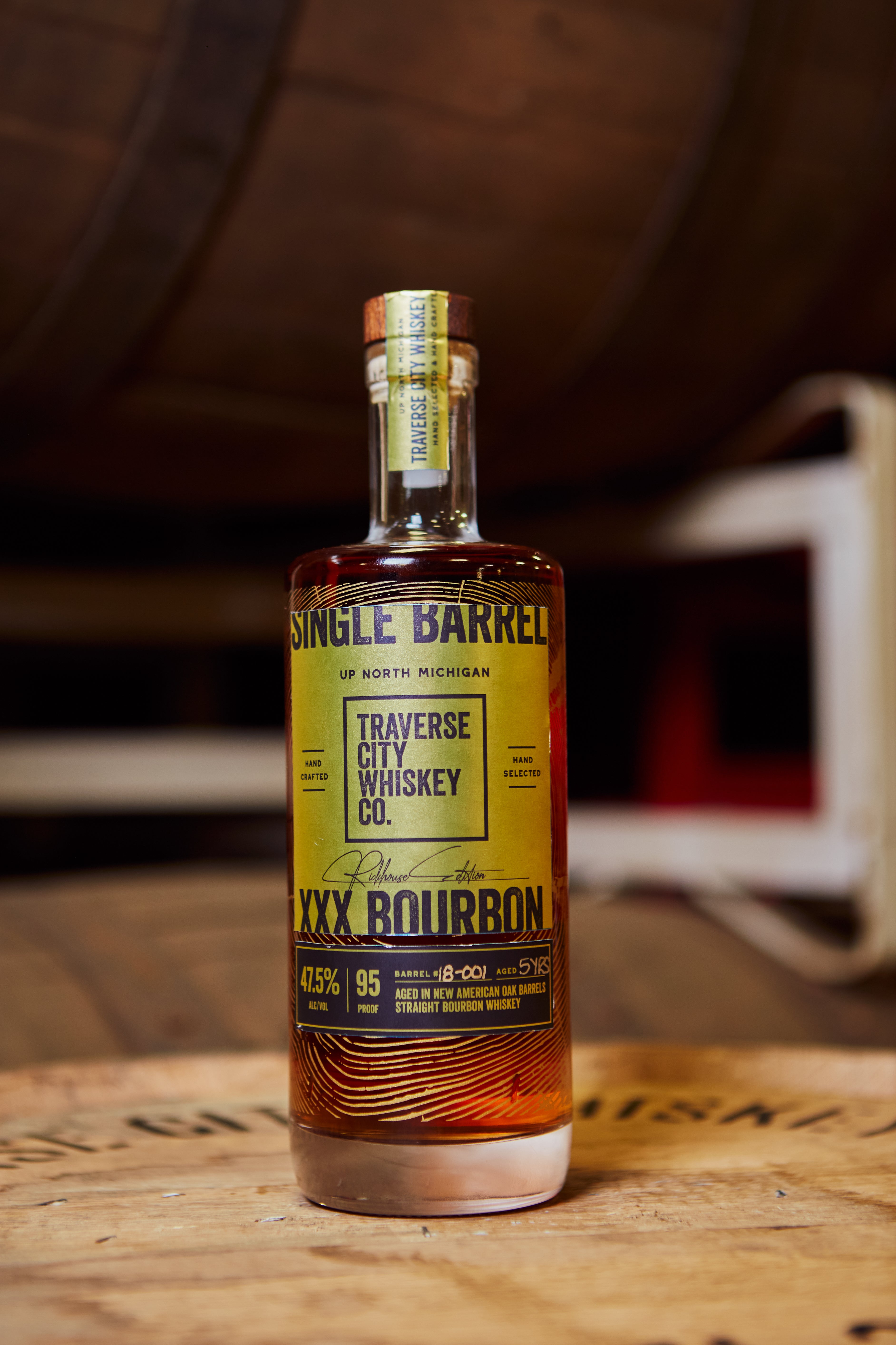 Single Barrel XXX Straight Bourbon bottle on a barrel