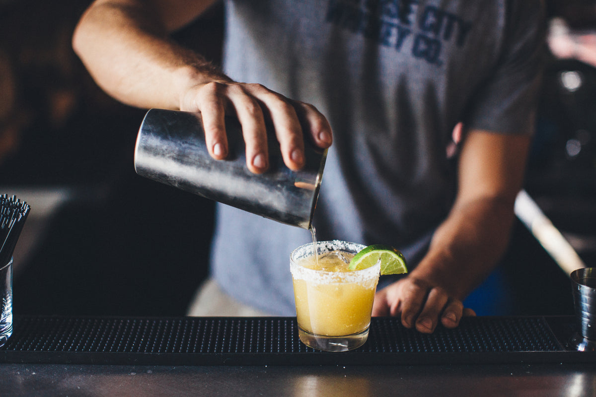 Bartender pouring a peach whiskey cocktail
