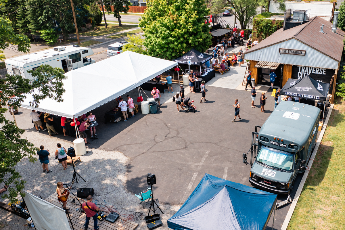 Aerial view of an outdoor event with tents and live music at the distillery