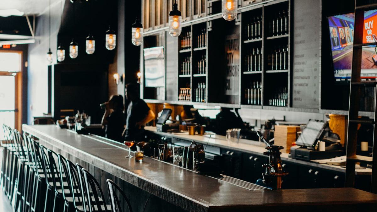 The bar at the Outpost tasting room in Ferndale, with stools along the counter and shelves of Traverse City Whiskey Co. bottles