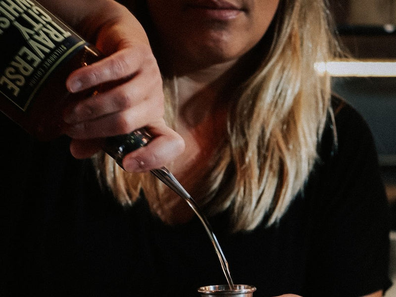 A bartender pouring Traverse City Whiskey Co. whiskey into a jigger at the Outpost