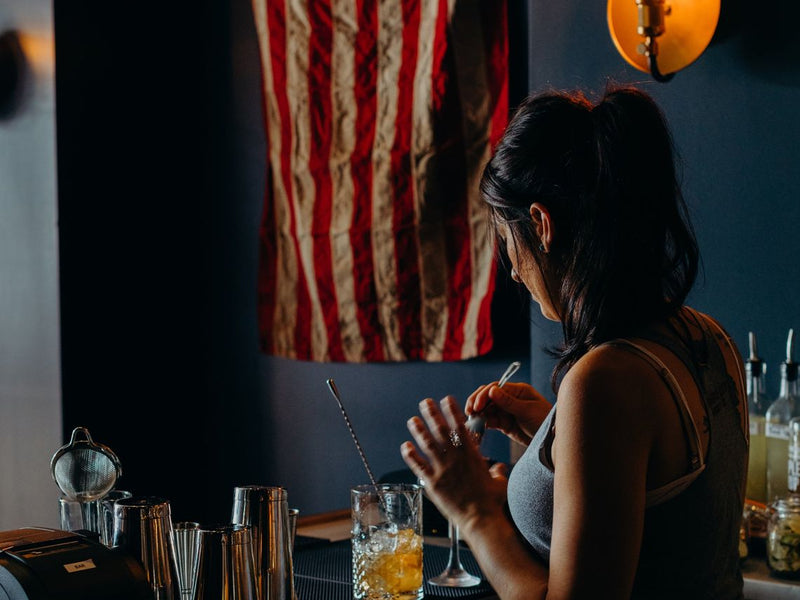 A bartender working the bar under the American flag at the Outpost